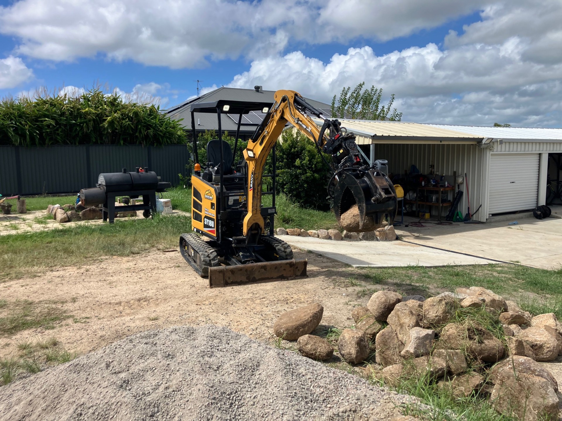 Mini excavator using a grab attachment on site