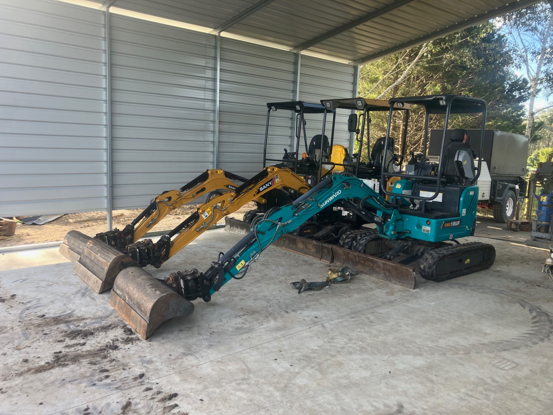Sany and Sunward mini excavators parked side by side in the workshop shed